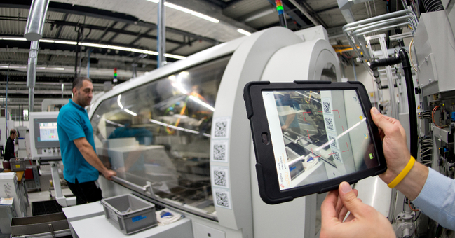 An employee with a tablet PC at the barcode on a machine